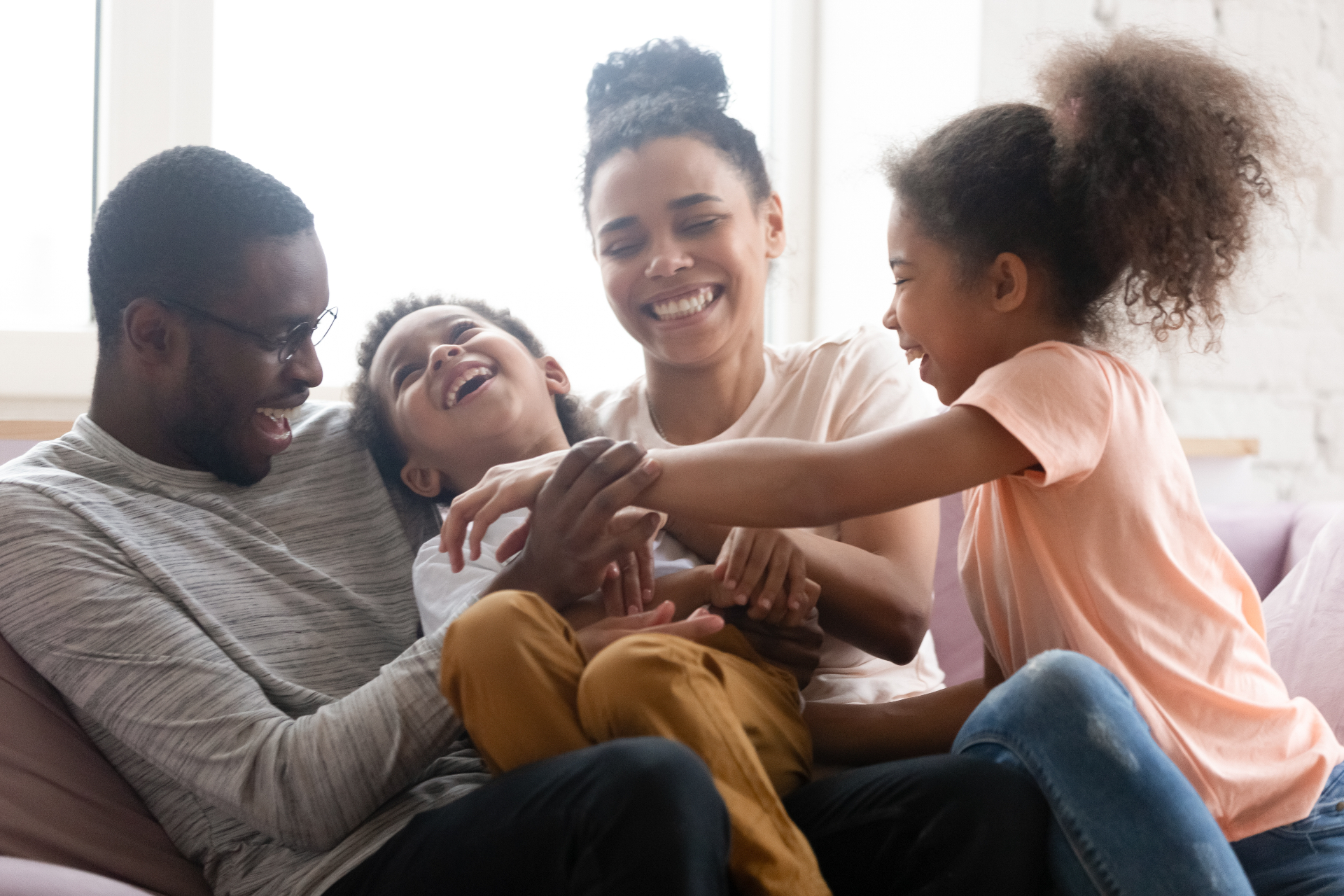 A happy family laughing together on the living room floor, bathed in warm sunlight