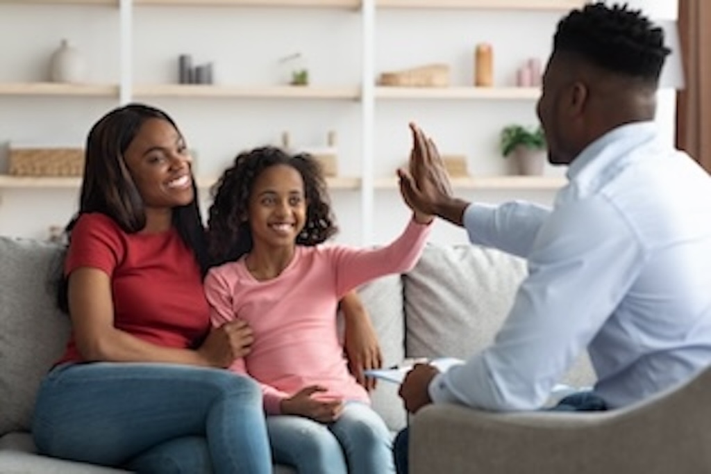 A warm family therapy session with a therapist and family in a bright, welcoming office